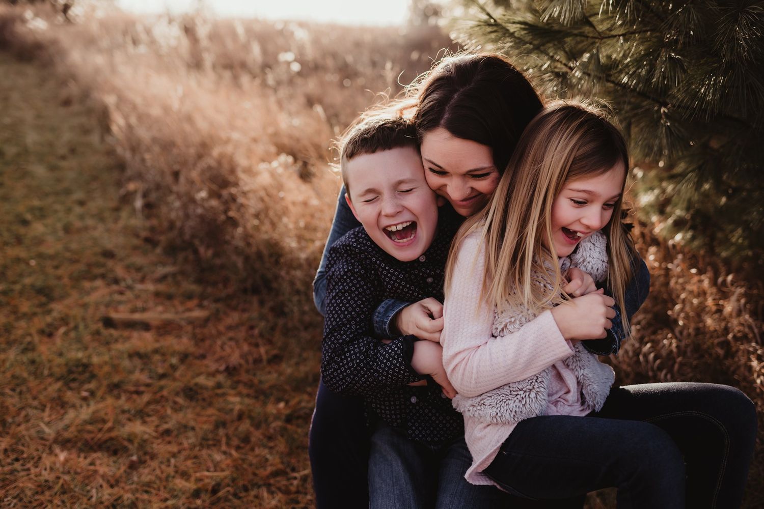 Candid moment of three people sharing laughter while sitting together outdoors.
