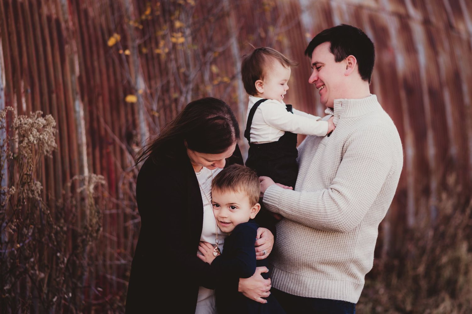 Candid family moment against a rustic red barn backdrop.