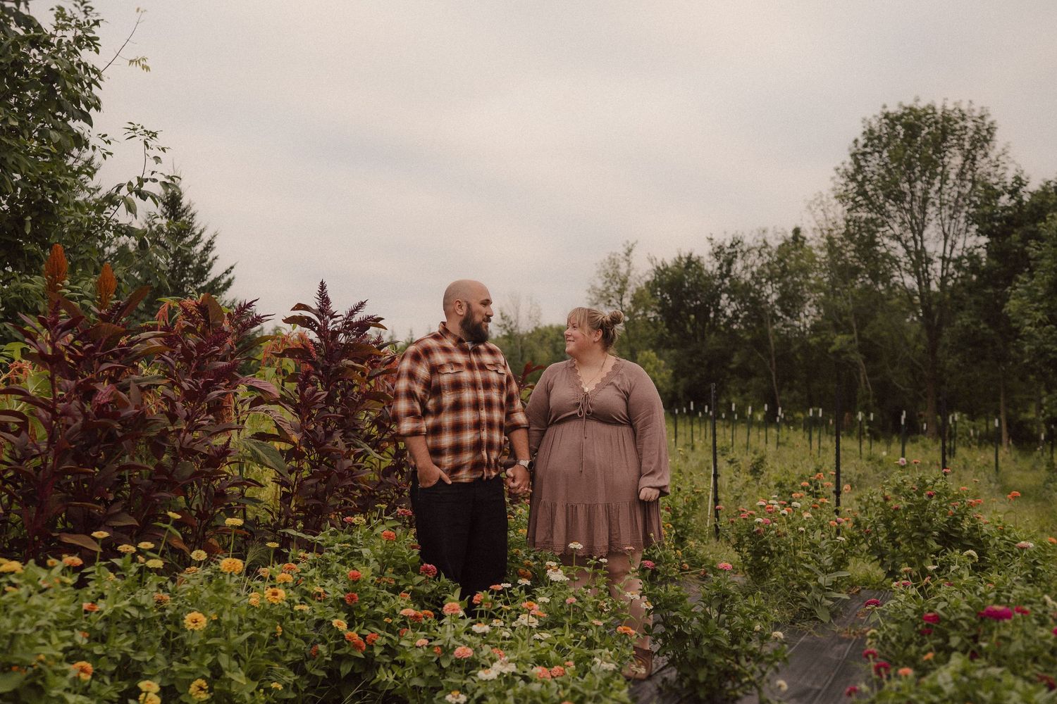 Two people stroll through a colorful wildflower garden filled with vibrant blooms on a summer day.