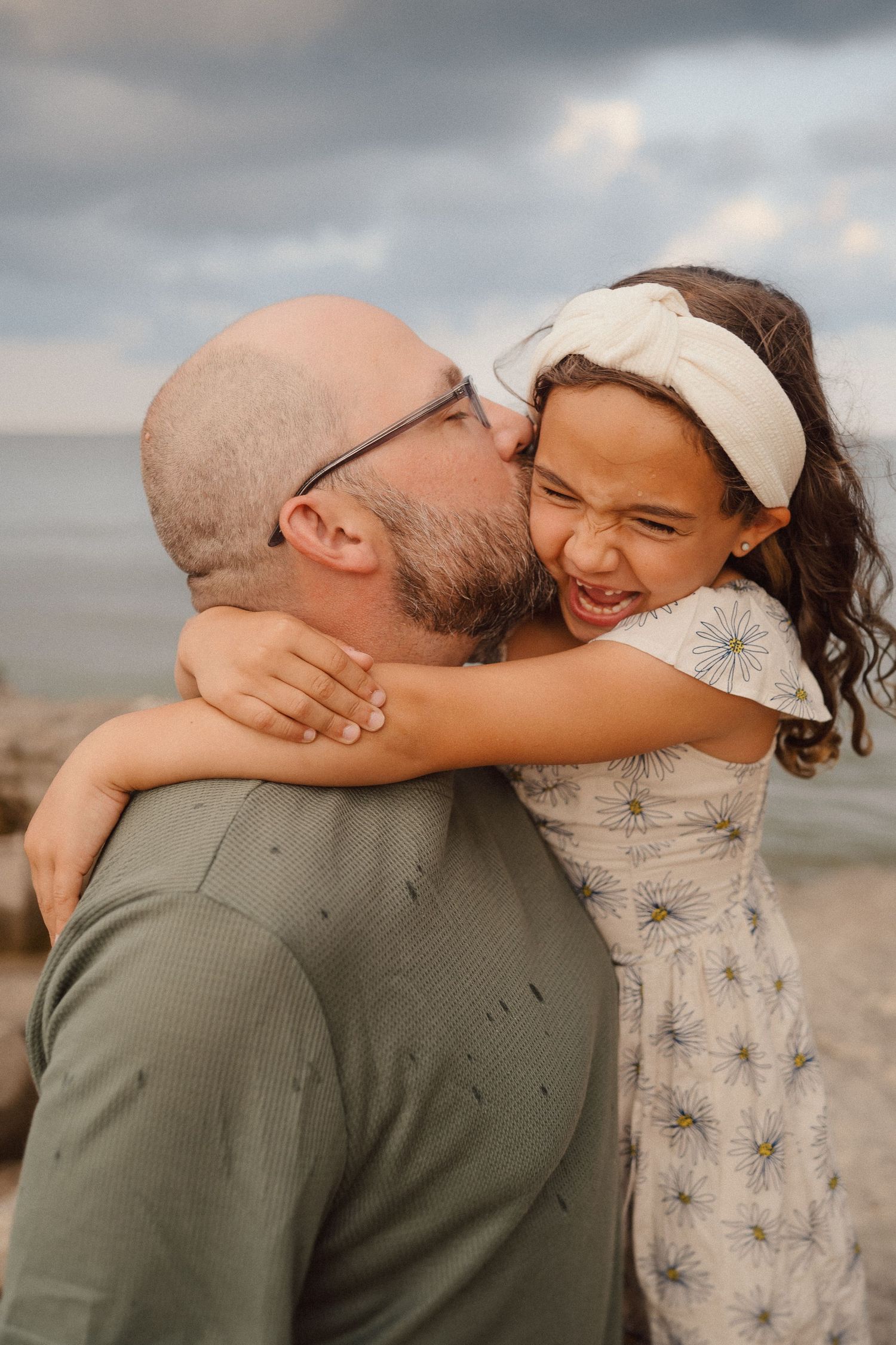 A tender beach moment is captured against a cloudy coastal backdrop.