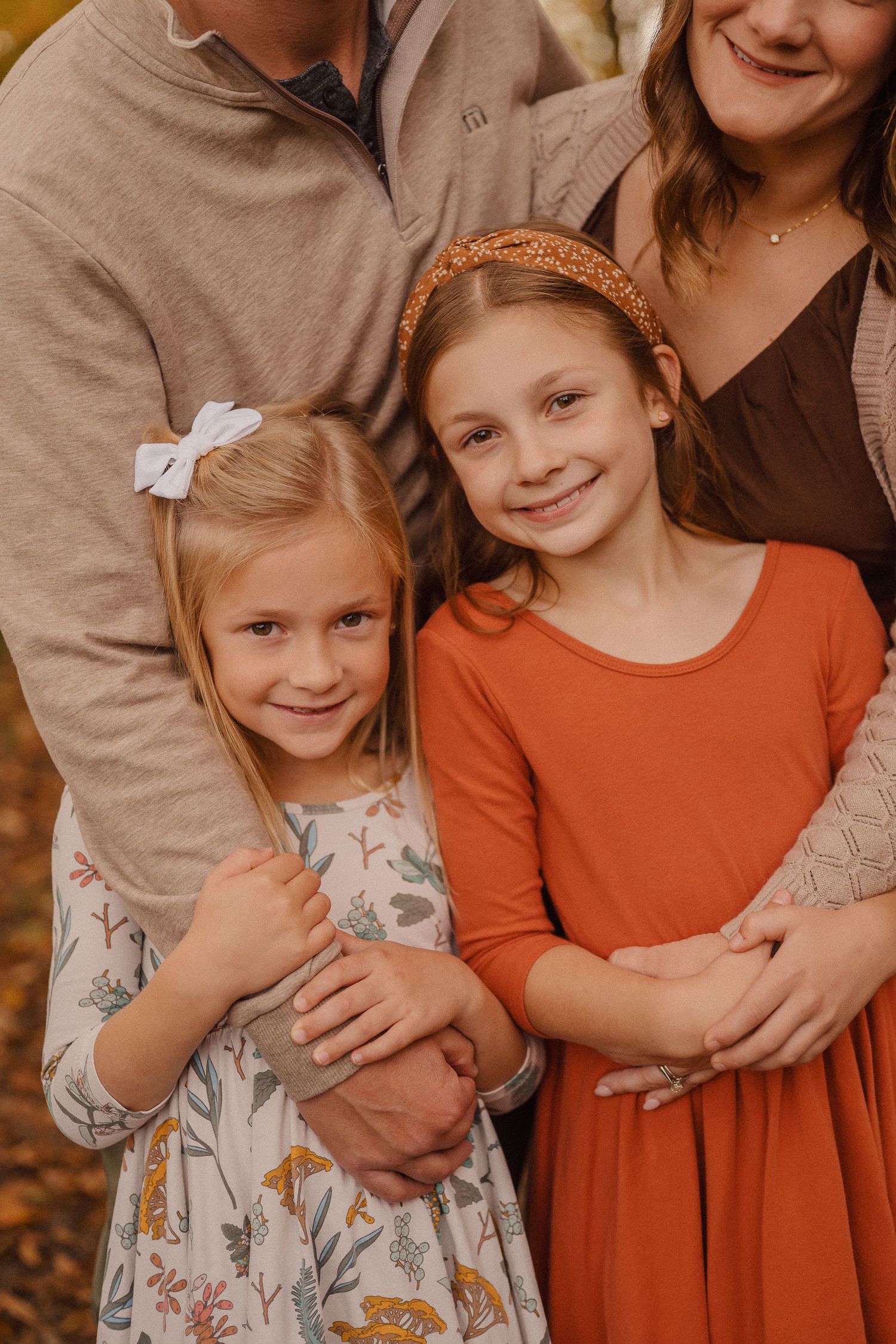 Family portrait featuring coordinated fall outfits in warm tones against an autumn background.