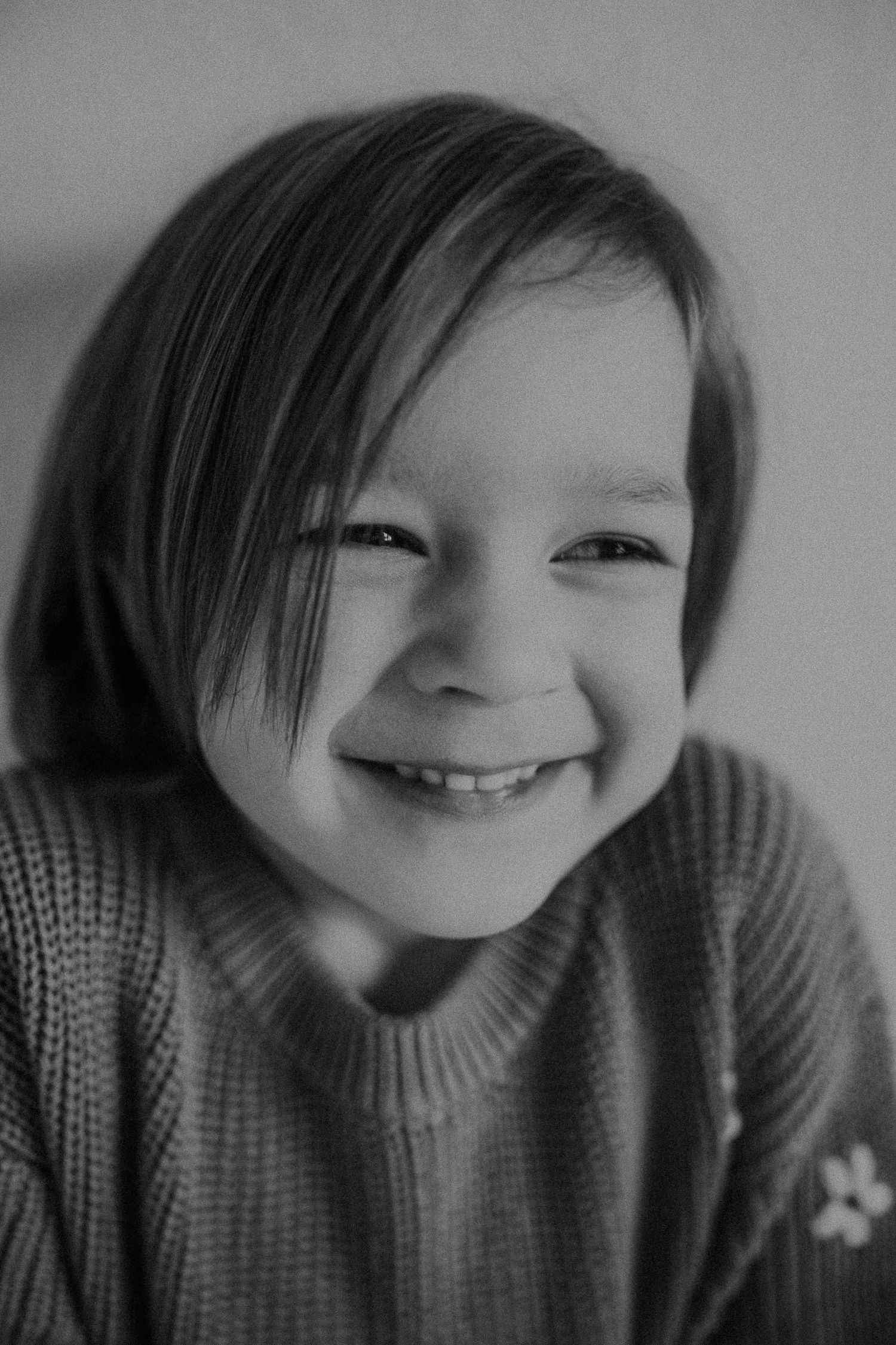 Black and white close-up photograph showing a joyful expression and cozy sweater.