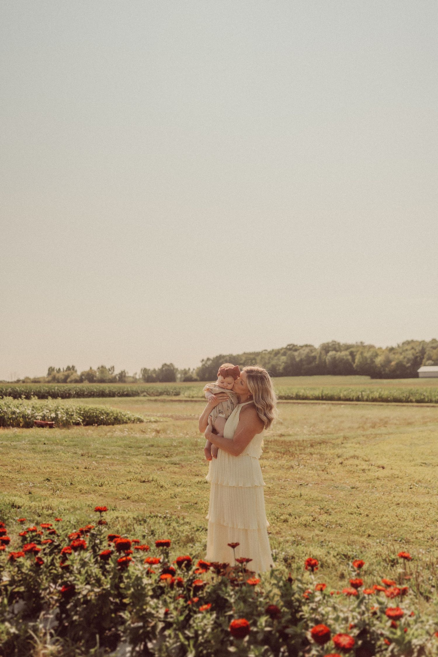 Ethereal sunset photo of figures standing among red flowers in a country field.