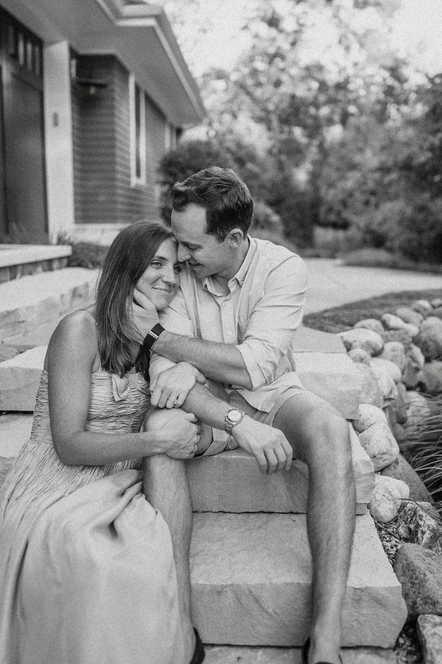 Couple shares a loving moment while sitting on stone steps outdoors.