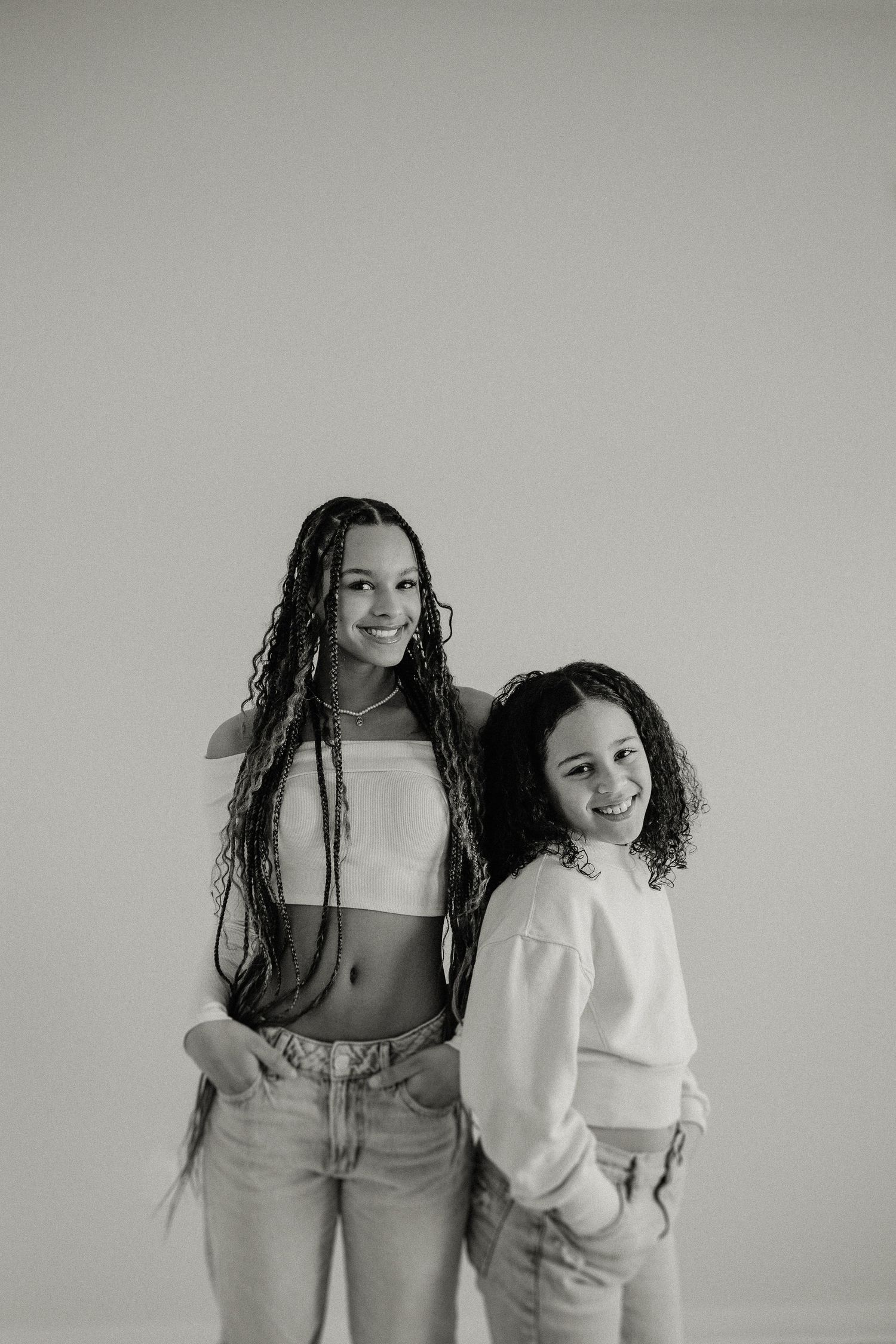 Black and white studio portrait of two people in casual attire against a plain backdrop.