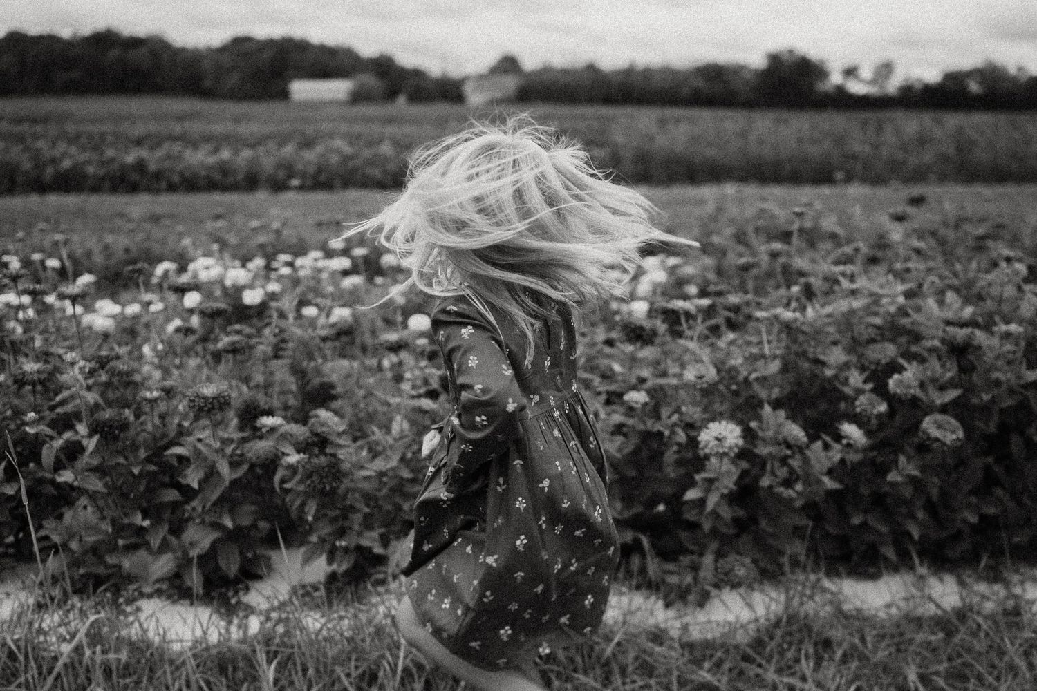 Black and white image capturing motion as someone spins in a flower field.