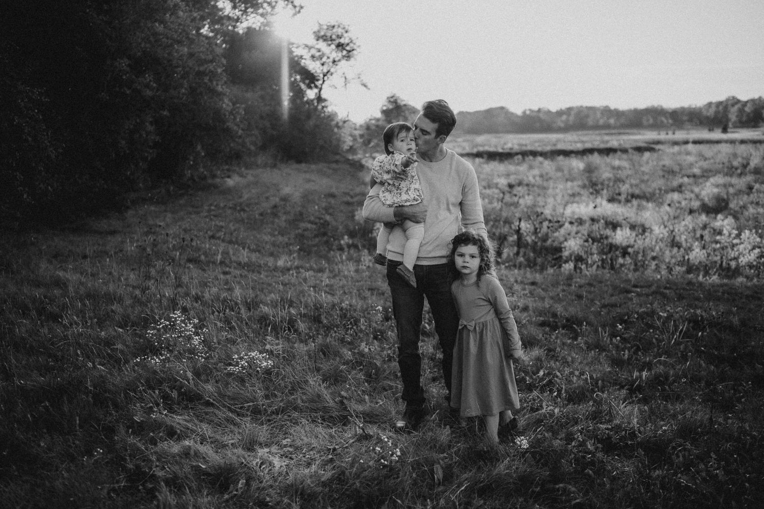 Black and white vintage-style family photograph taken in a rural field setting.
