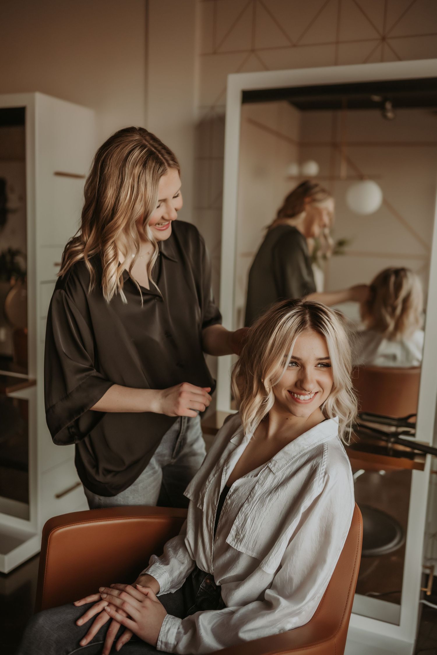 Salon styling session captured in warm tones with mirror reflections and modern decor.