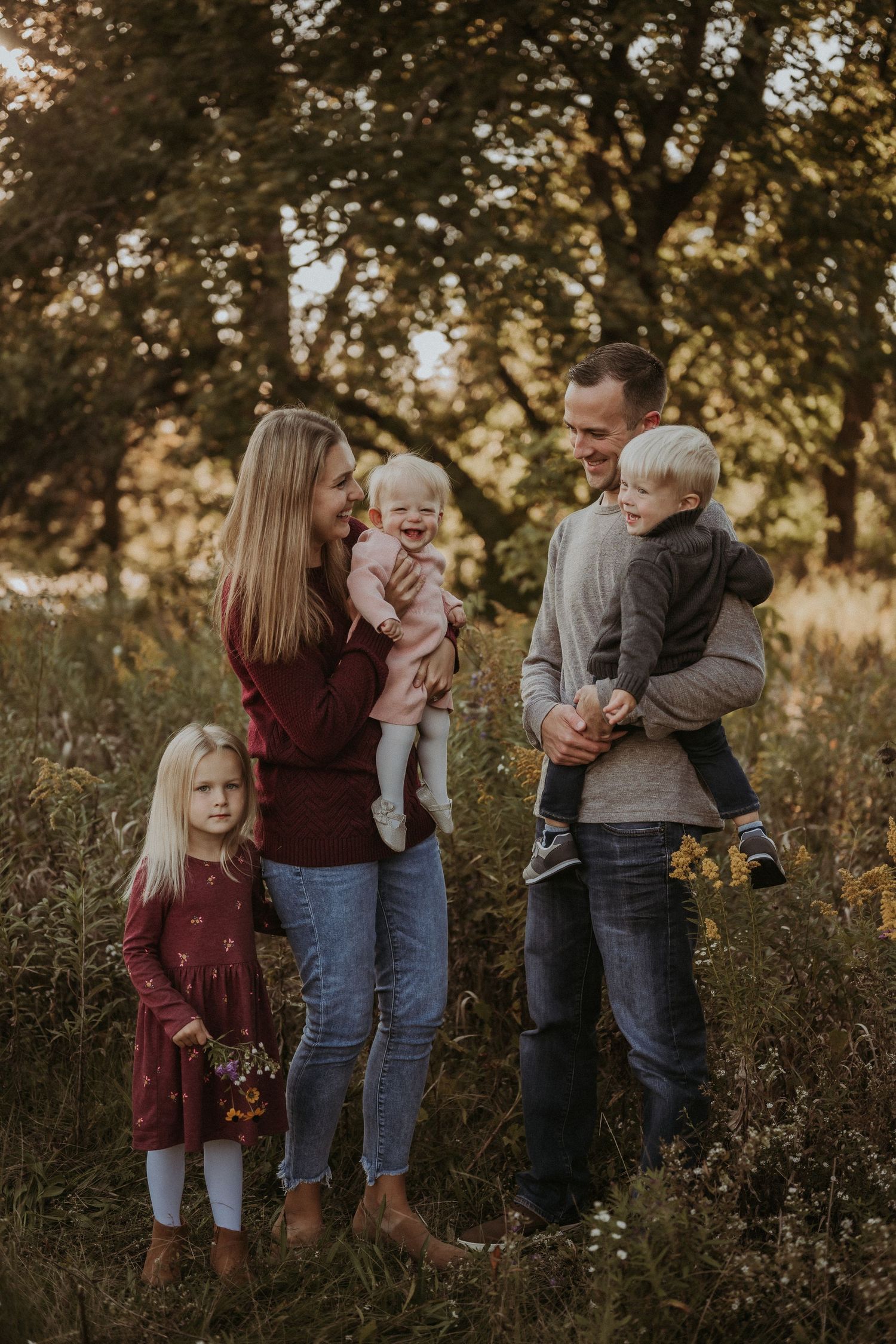 Natural light family portrait in rustic outdoor setting during golden hour.