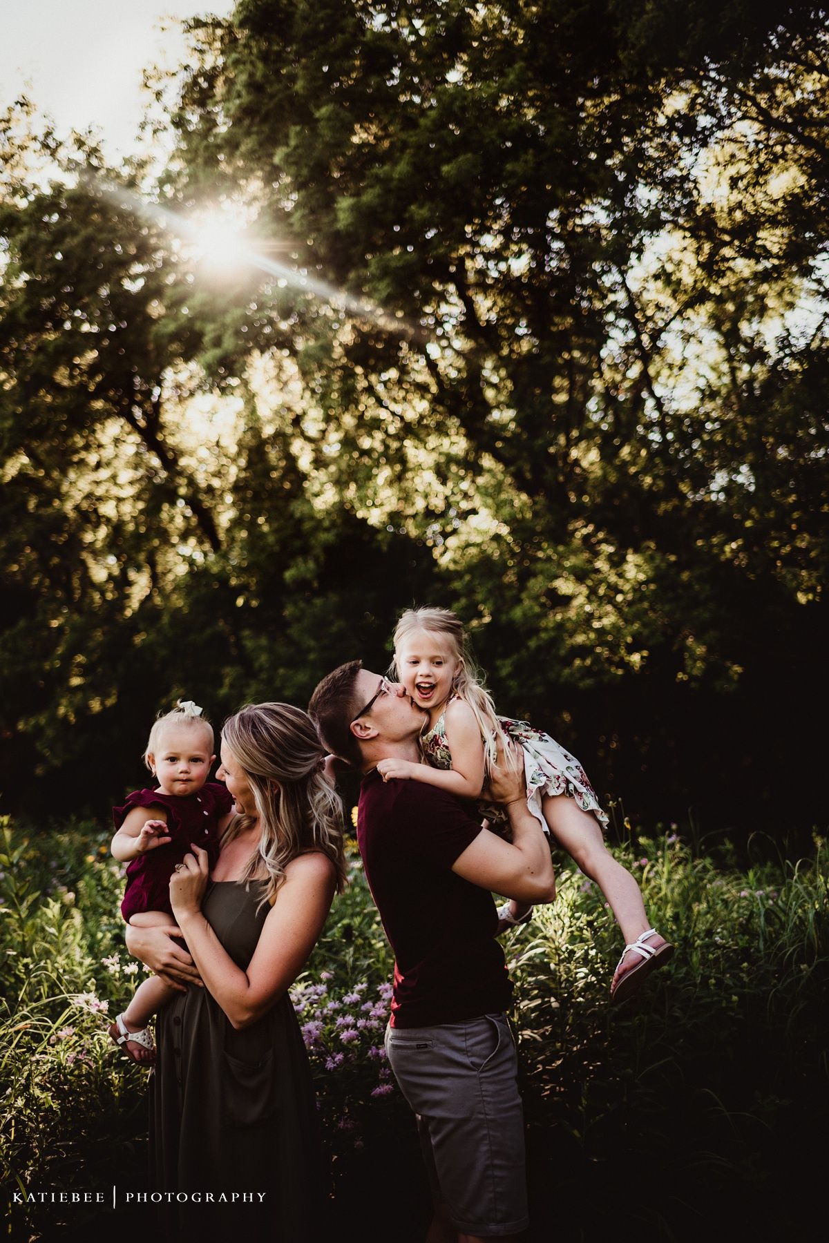 Silhouetted family portrait at sunset with sunburst through trees.