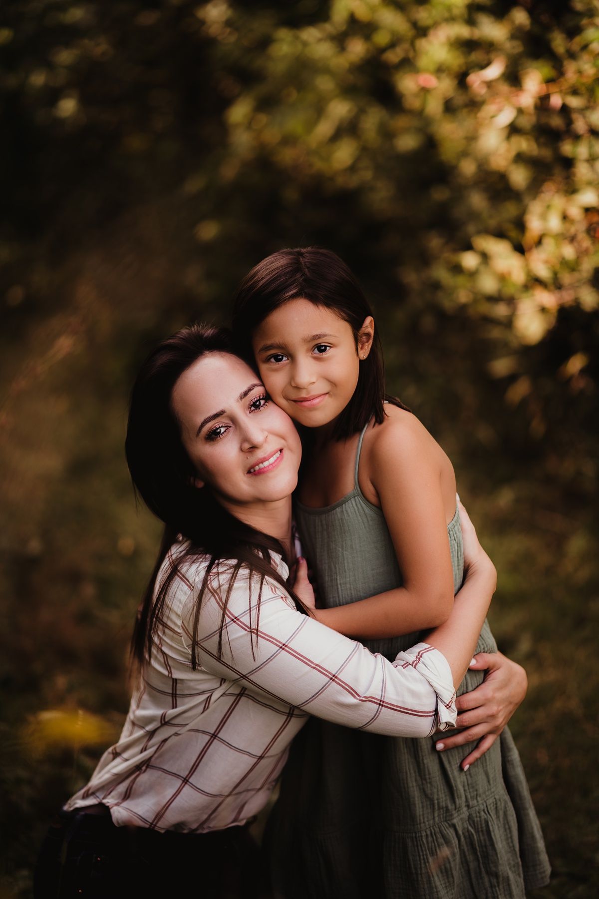 Sweet outdoor portrait of mother and daughter hugging and smiling together.