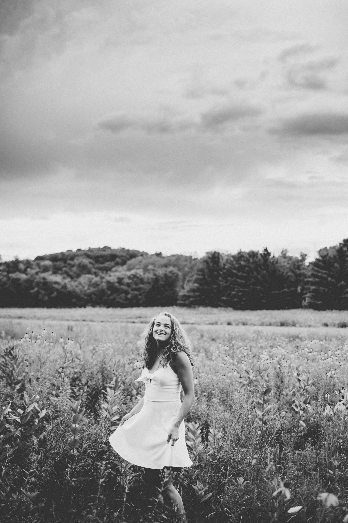 Black and white photo of dancing in meadow with mountains in background.