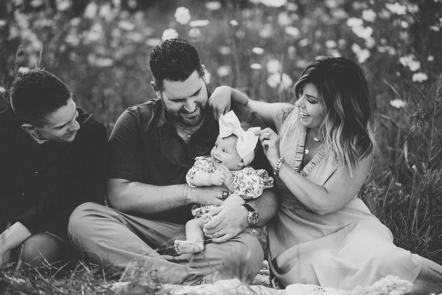 A family sitting together in a wildflower field during a casual outdoor photo session.