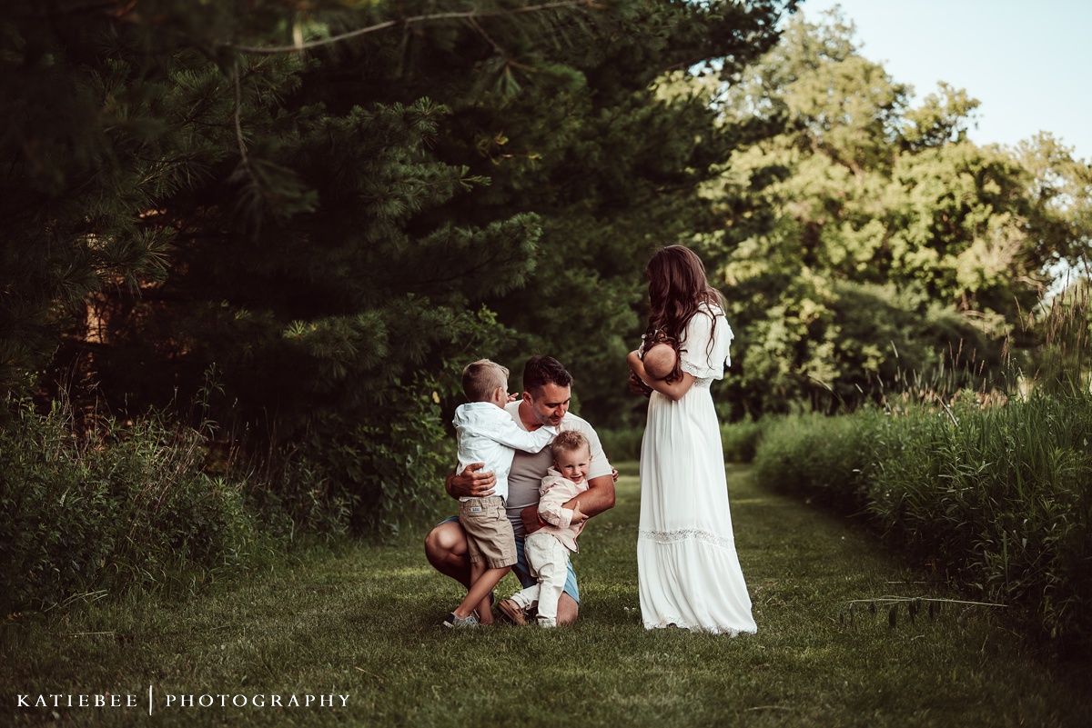 Family enjoying a playful moment together in a sunlit garden setting.
