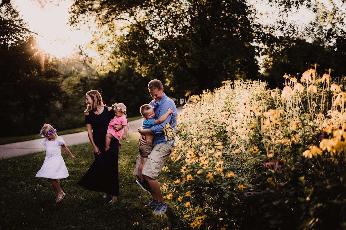 Family walking together on a path during sunset with golden light filtering through trees.