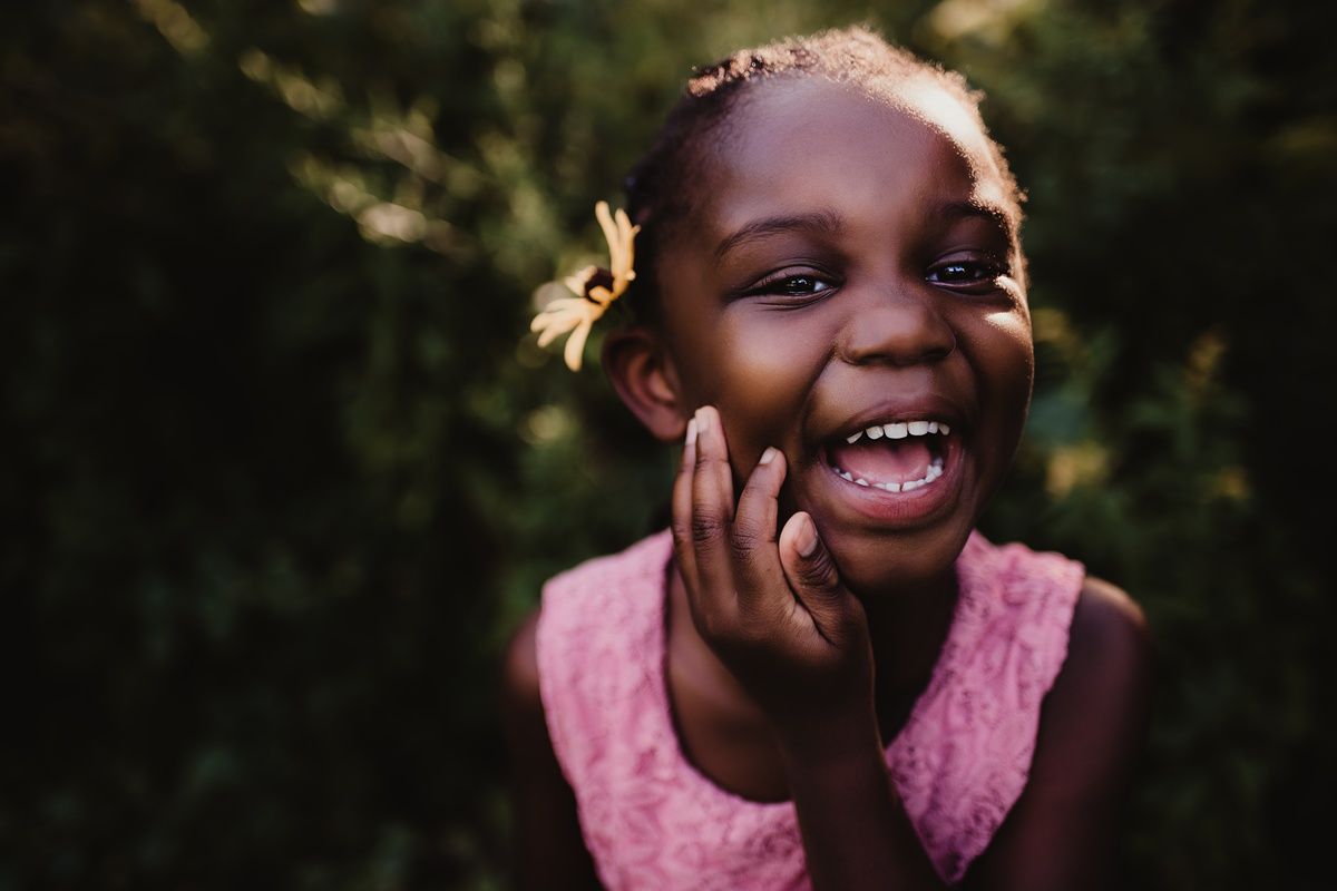 A candid portrait showing pure joy and laughter in a natural outdoor setting.
