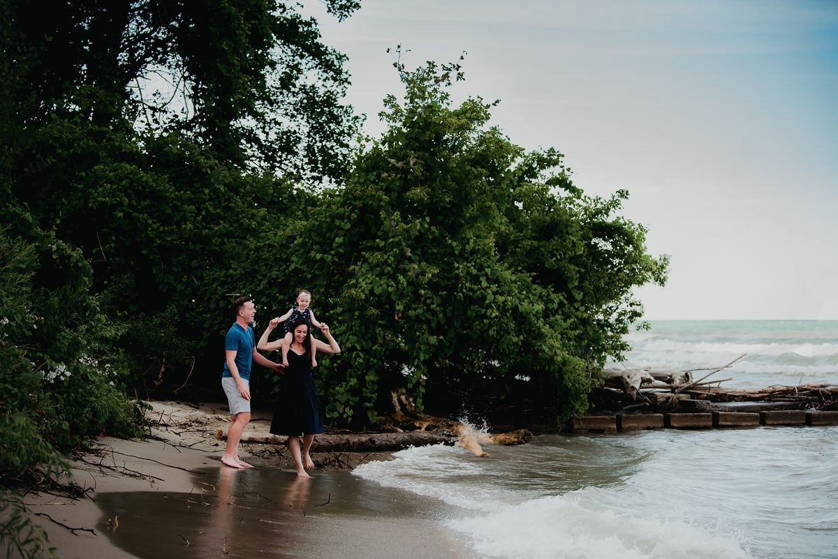 A family enjoys a peaceful moment together on a beach with dense foliage in the background.