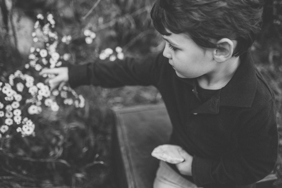 Black and white portrait of someone examining white flowers in nature.