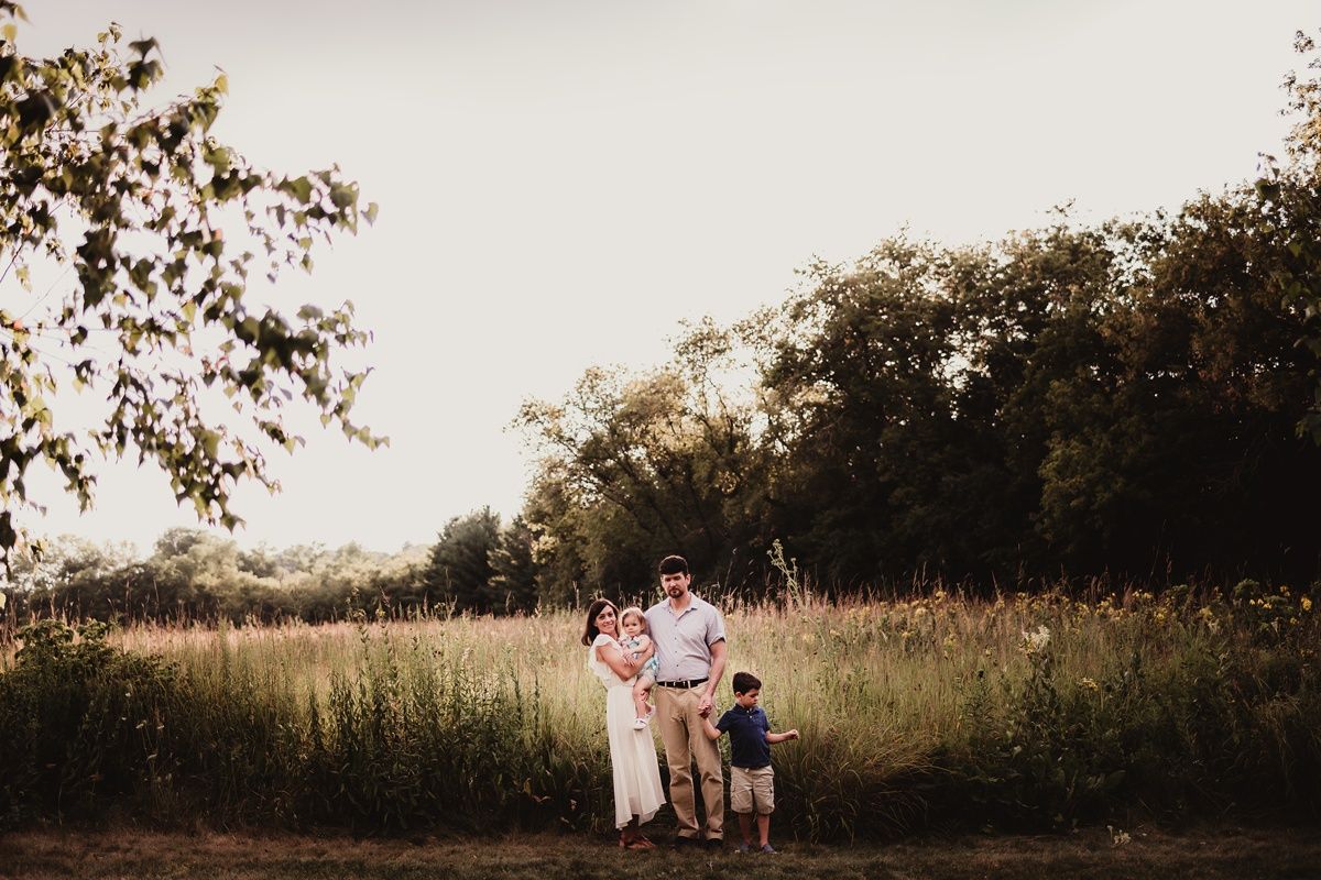 Silhouetted family walking together through a golden field at sunset.