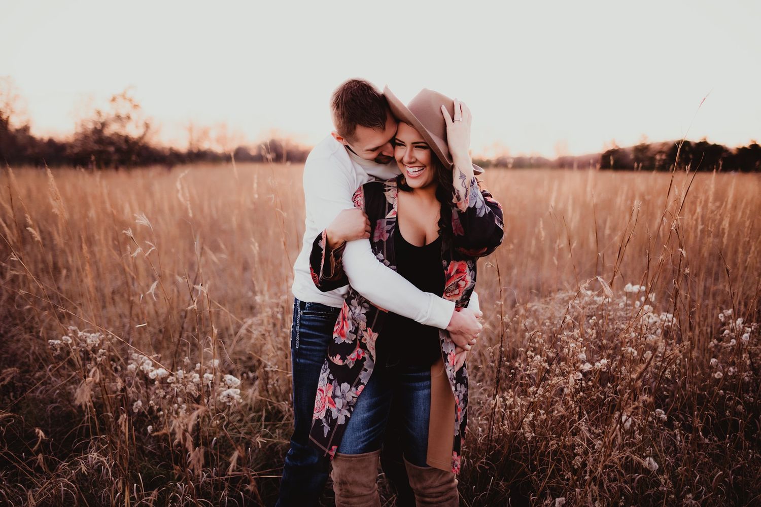 A tender embrace captured in warm tones amidst a field of tall grass.