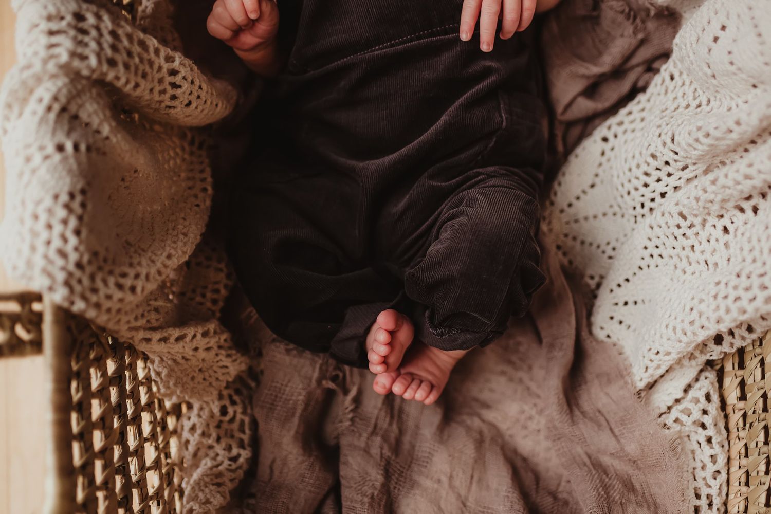 Close-up detail of tiny feet and hands resting on textured knit blankets.