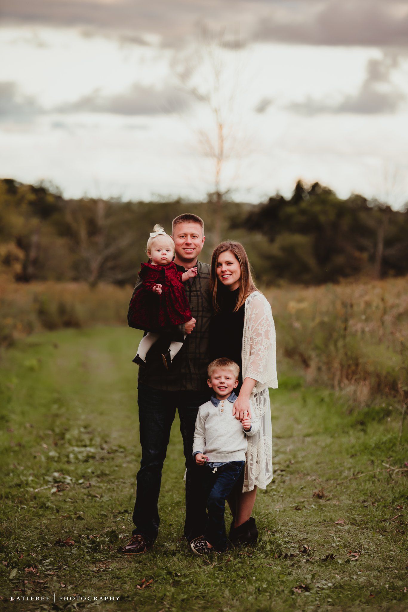 A loving family portrait taken on a country path surrounded by lush greenery.