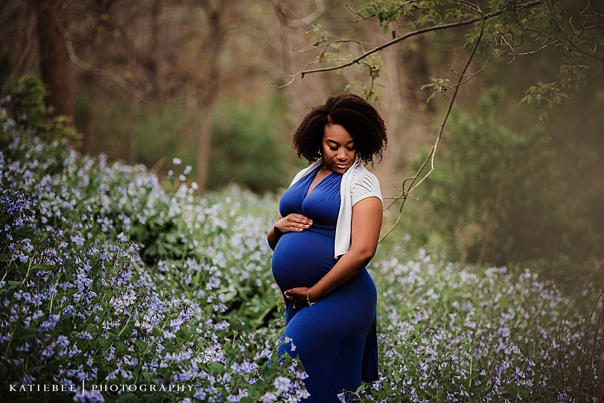 Maternity portrait in blue dress surrounded by blooming purple wildflowers.