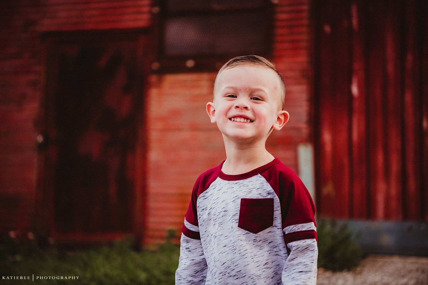 A cheerful expression captured against a vibrant red barn backdrop.