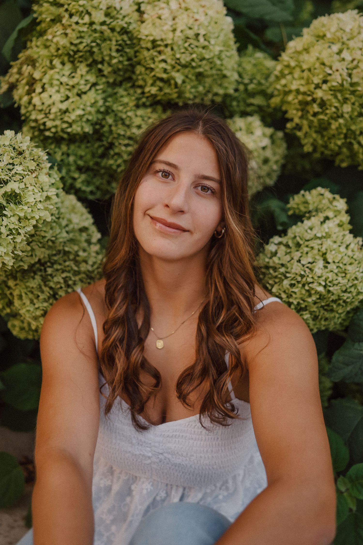 Summer portrait framed by blooming hydrangea bushes in natural lighting.