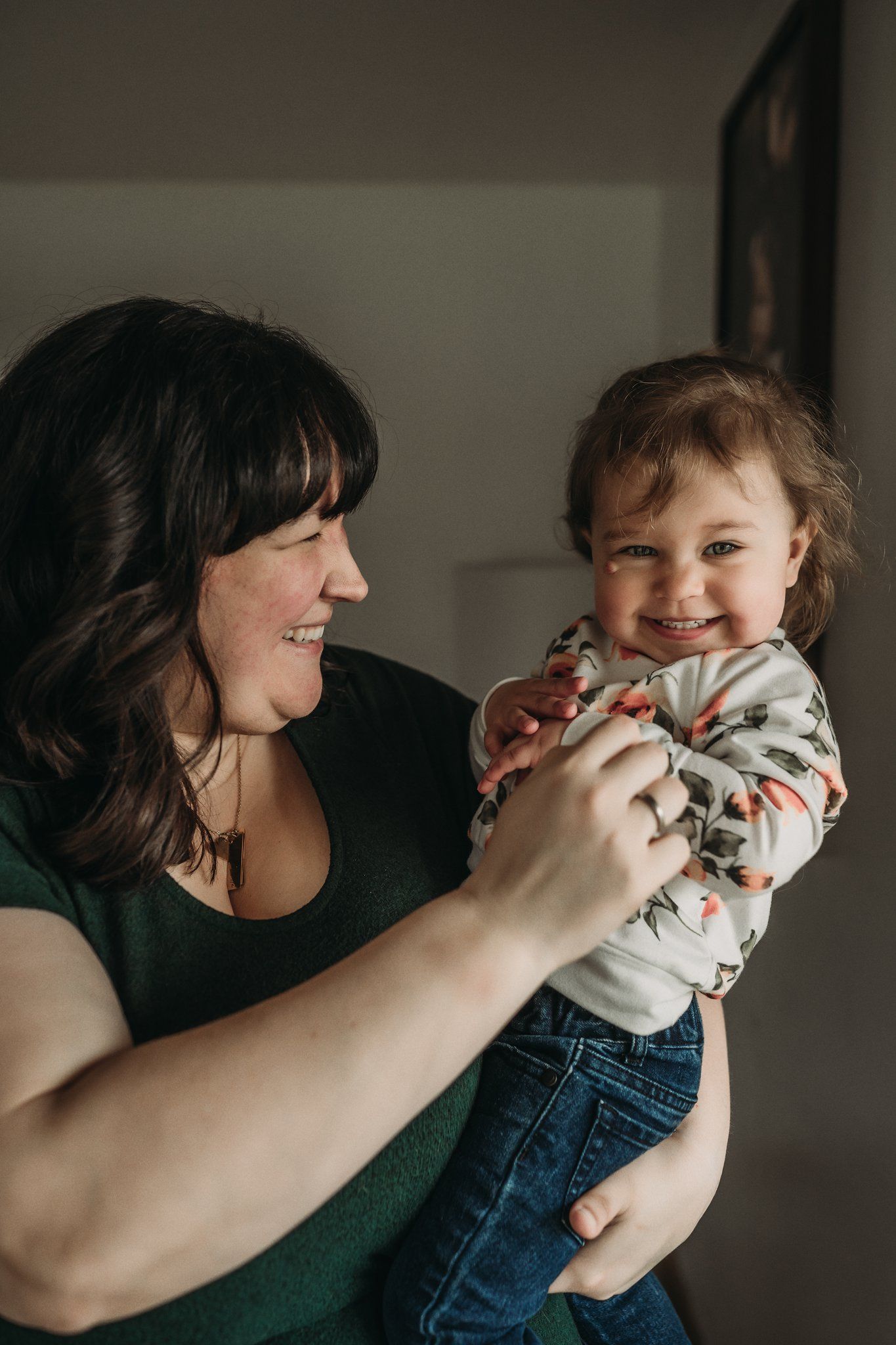 Joyful interaction between adult and toddler wearing floral print and denim.
