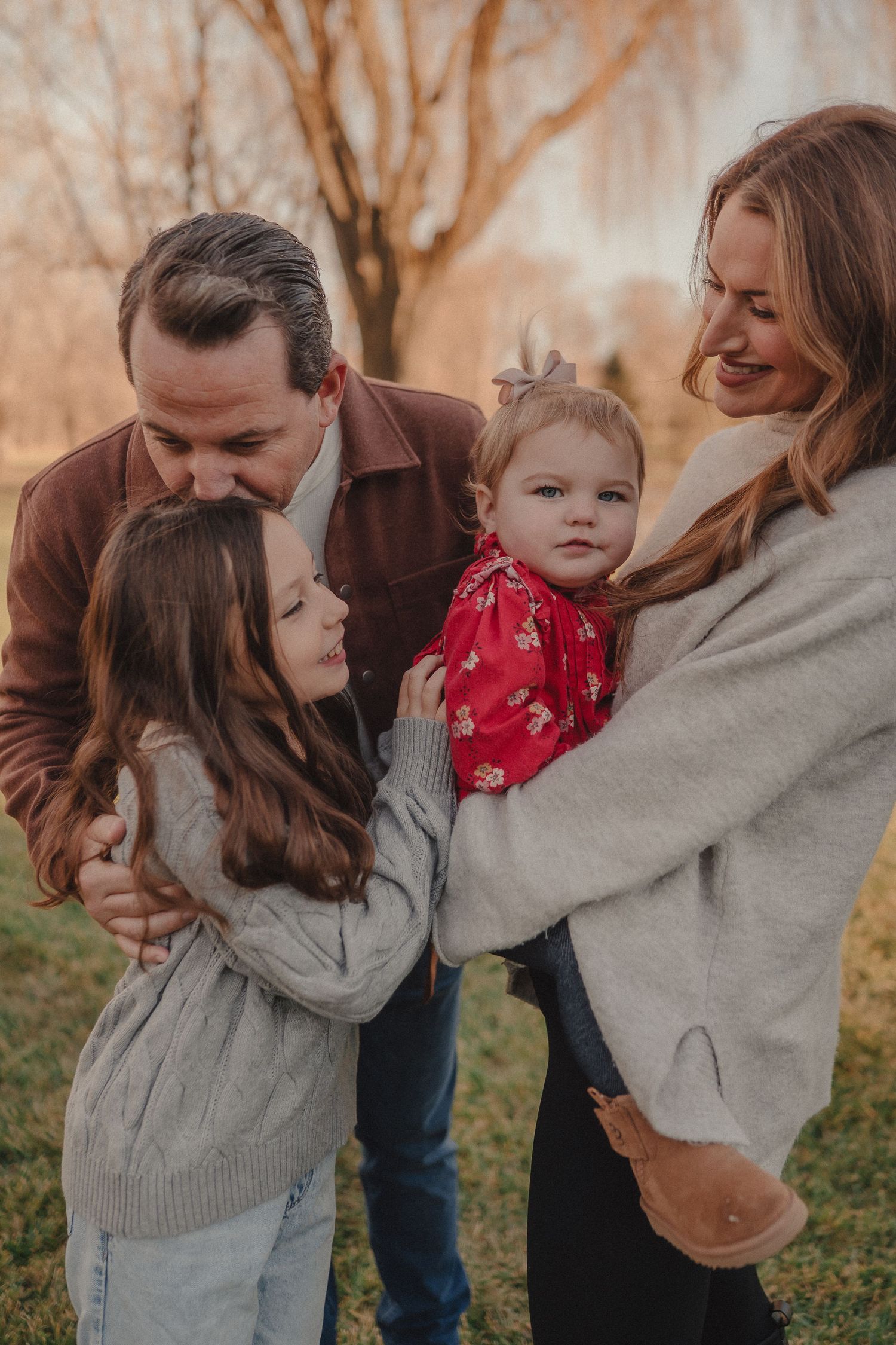 A family shares a tender moment outdoors during golden hour, wearing cozy sweaters in autumn.