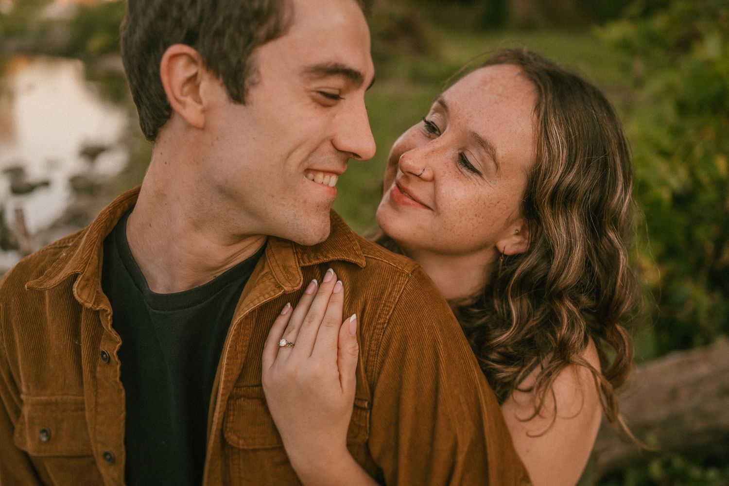 An intimate couple shares a loving moment outdoors while wearing casual autumn attire.