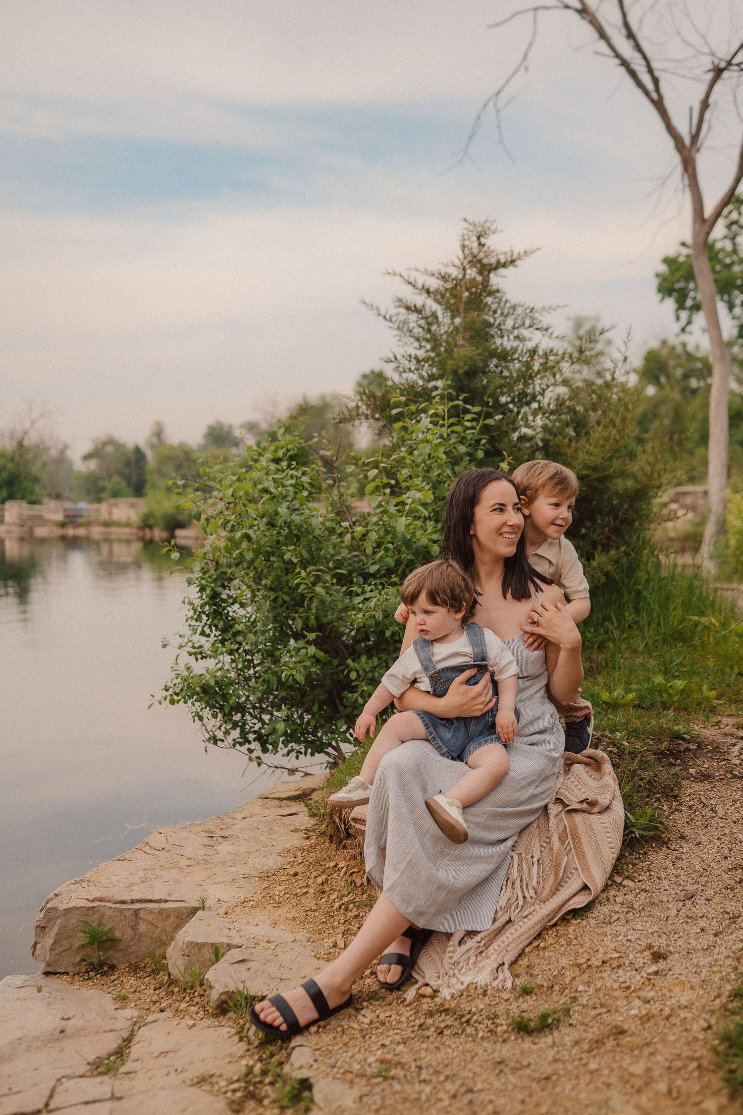 A family enjoys a peaceful moment together sitting by a tranquil lake on a summer evening.