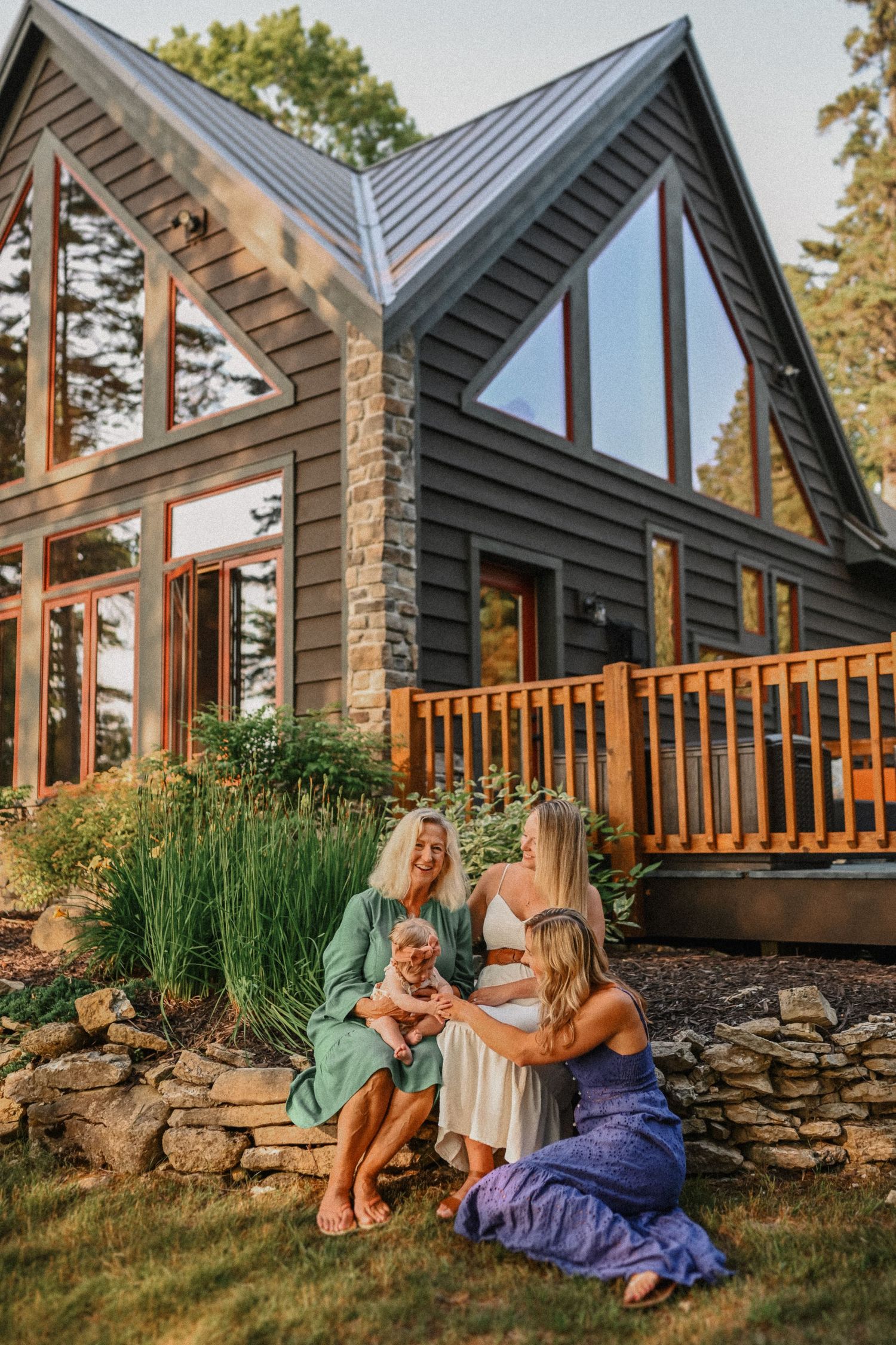 A modern A-frame house with large windows serves as backdrop for an outdoor gathering.
