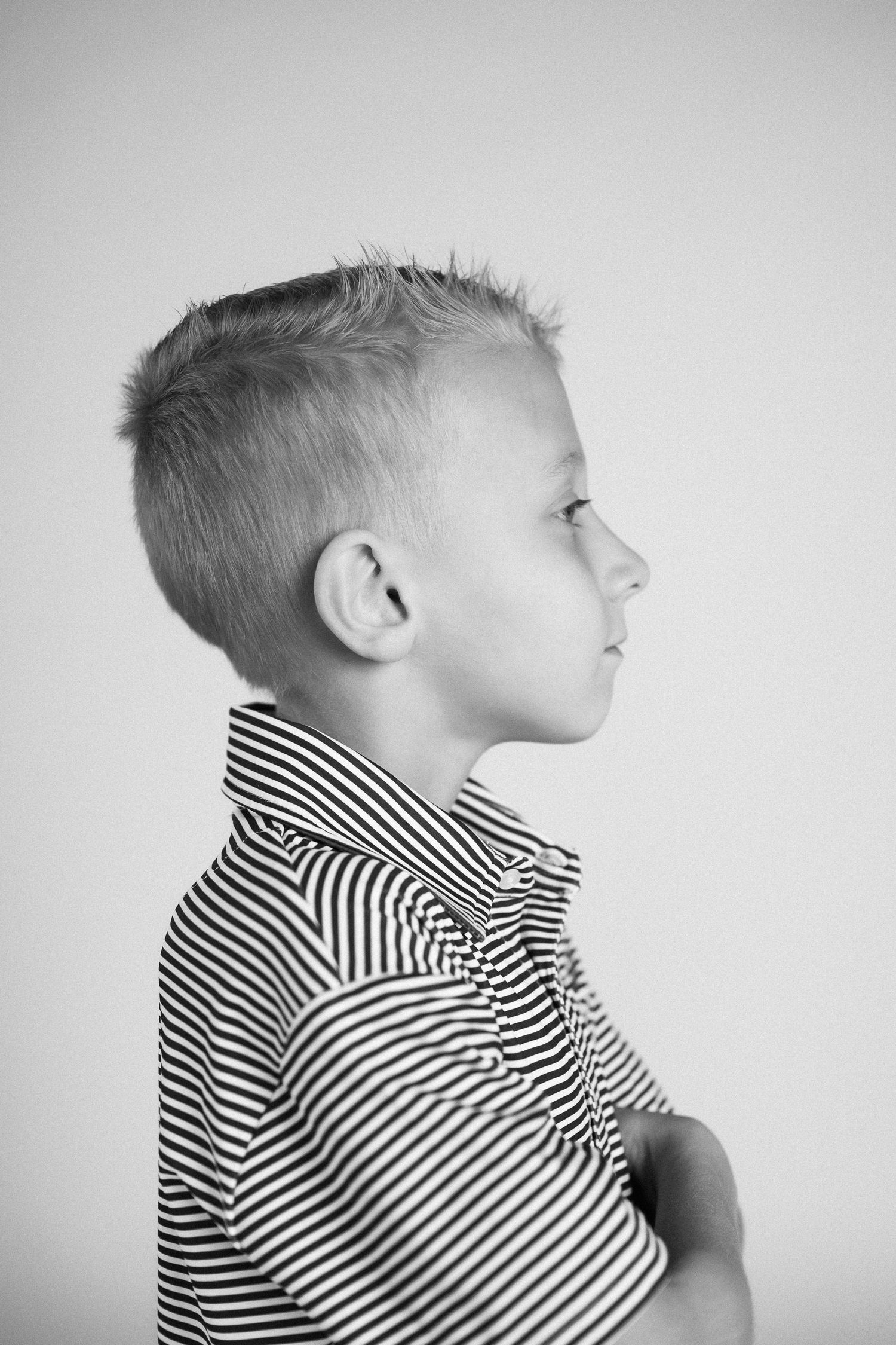 Black and white profile portrait of a child wearing a striped collared shirt against a plain background.