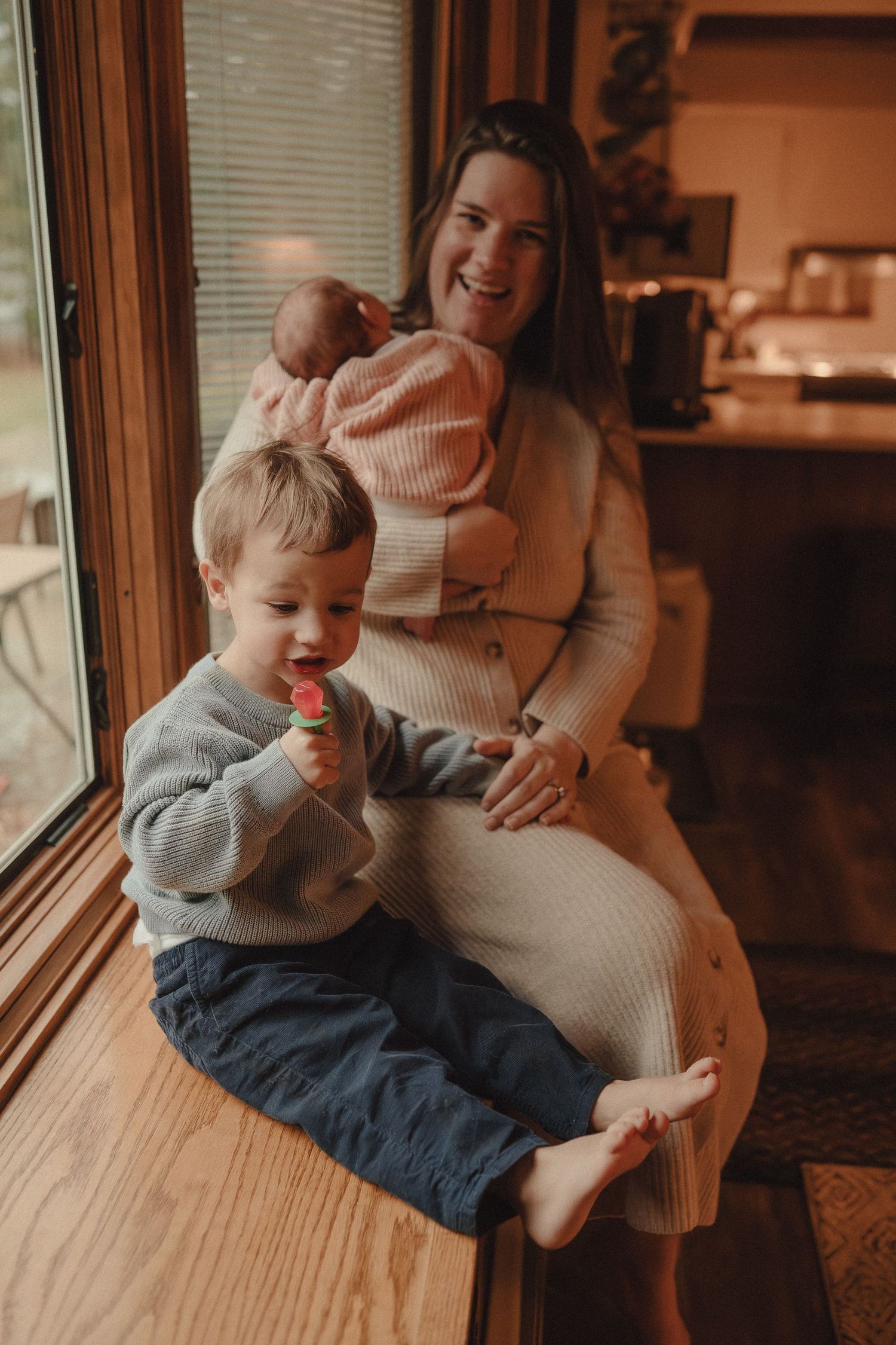 A joyful moment shared between family members sitting by a window in warm lighting.