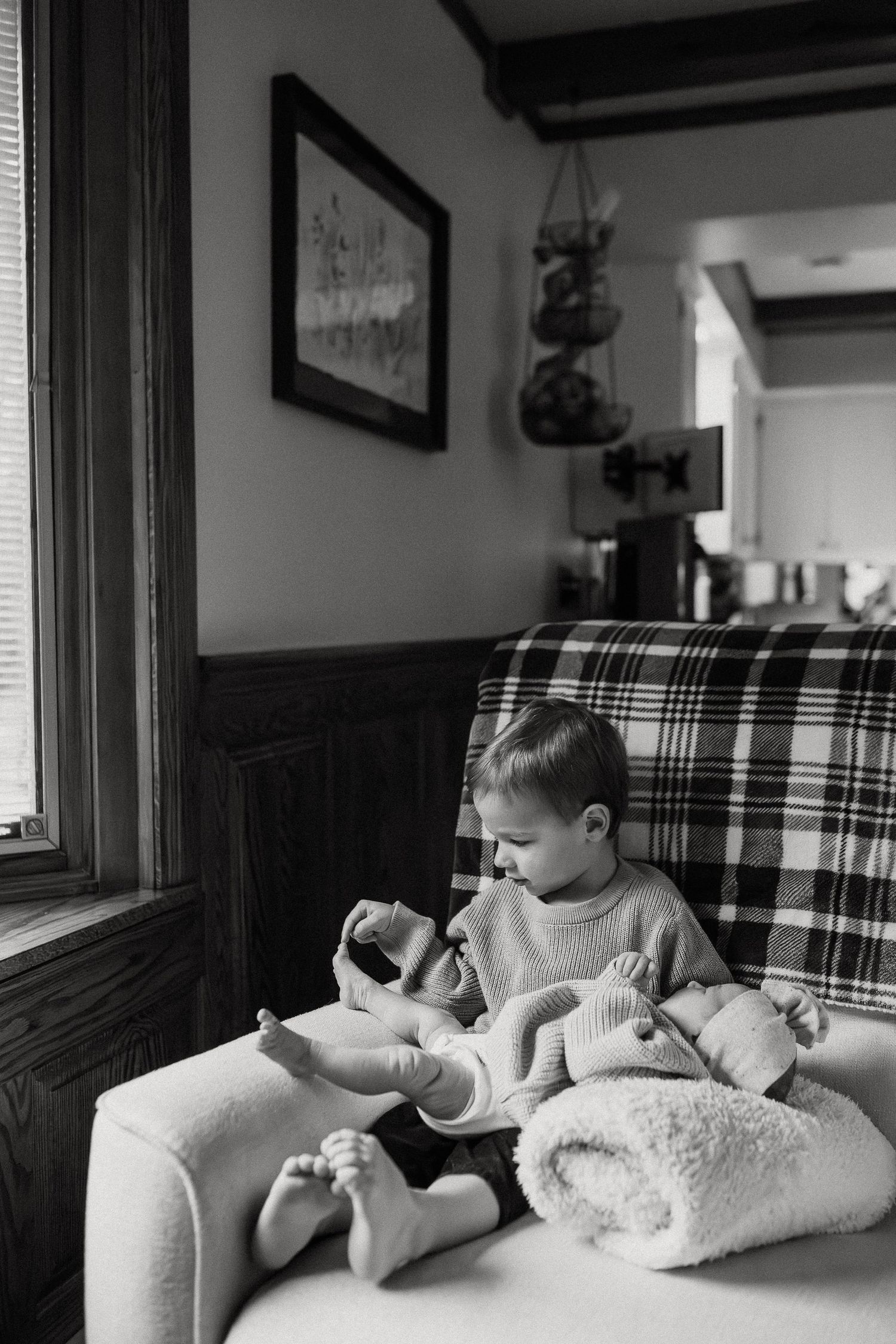 Black and white photo of a peaceful sleeping figure in a cozy plaid chair.