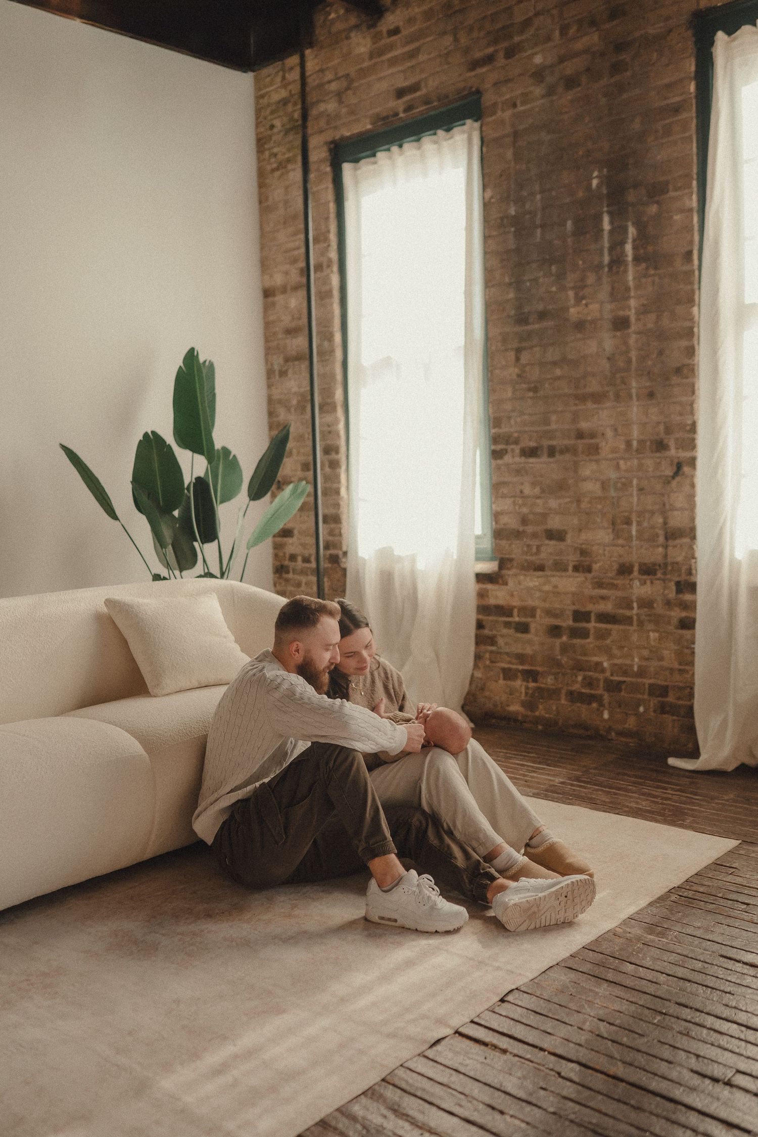 Intimate lifestyle photography session in a rustic studio with exposed brick walls and natural window light.