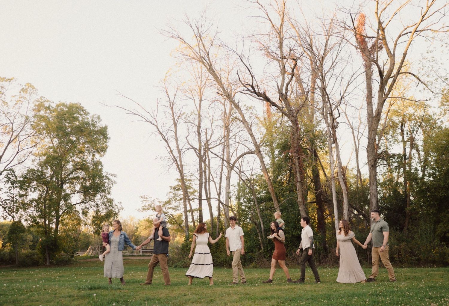 Family photoshoot in a natural setting with bare trees at dusk.