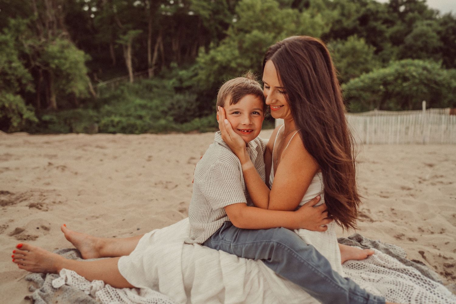 Intimate outdoor beach moment between two people sitting on a blanket.