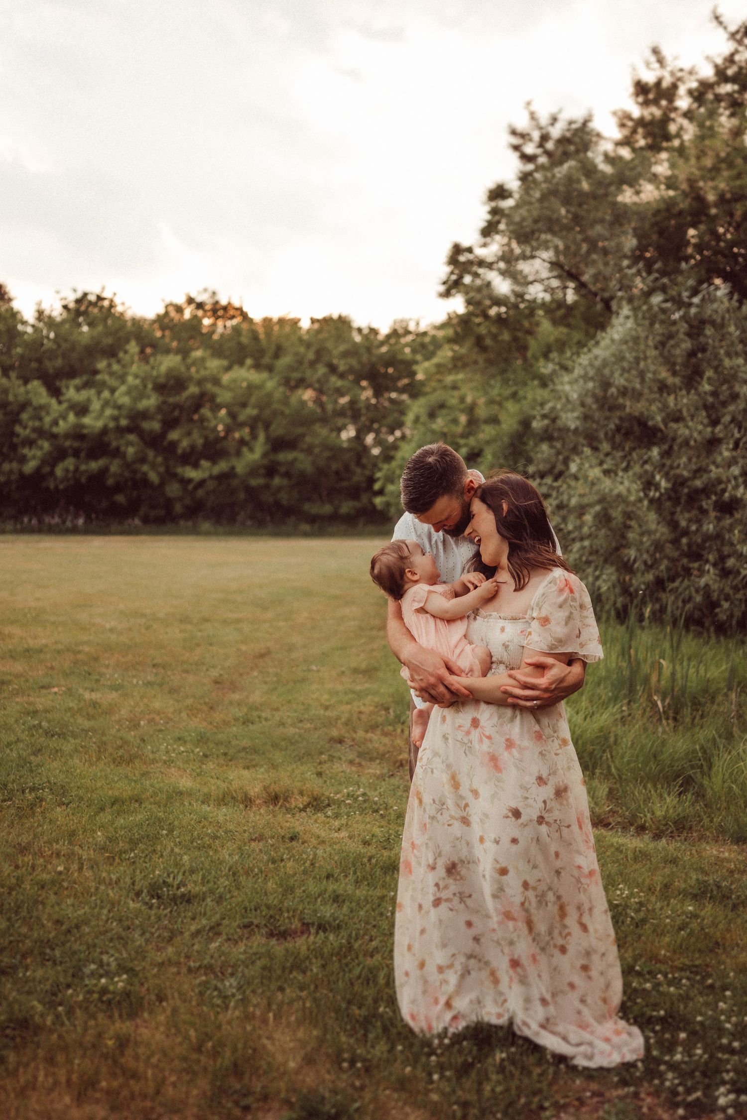 A romantic sunset portrait in a meadow wearing a flowing floral dress.