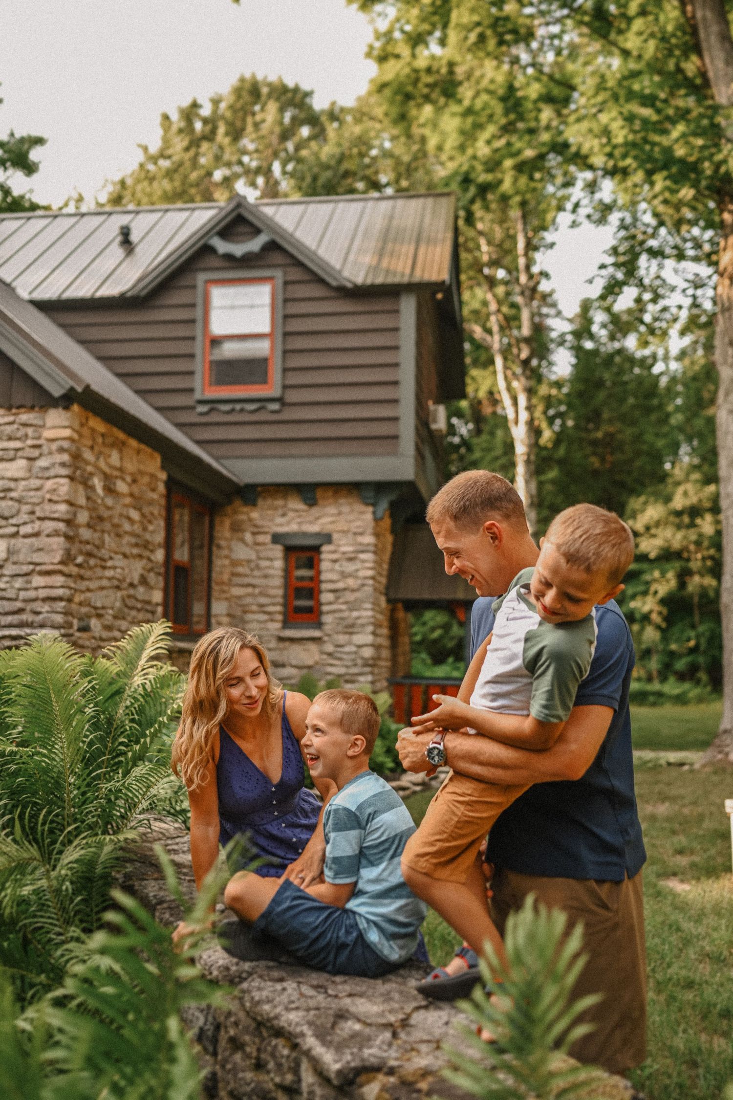 Happy family moment captured outside rustic cabin surrounded by natural landscaping.