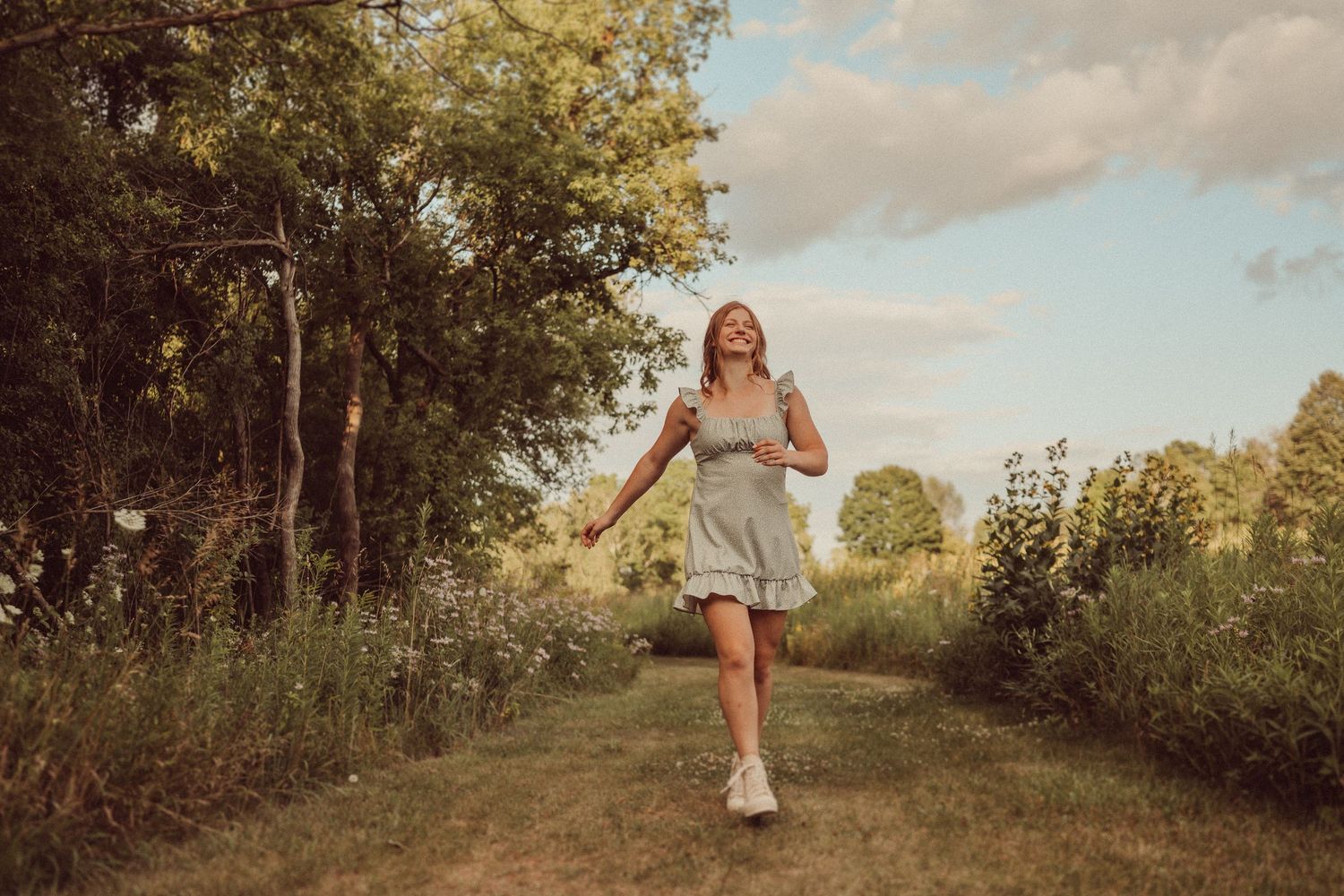 Playful summer scene on a garden path with a flowing dress and casual sneakers.