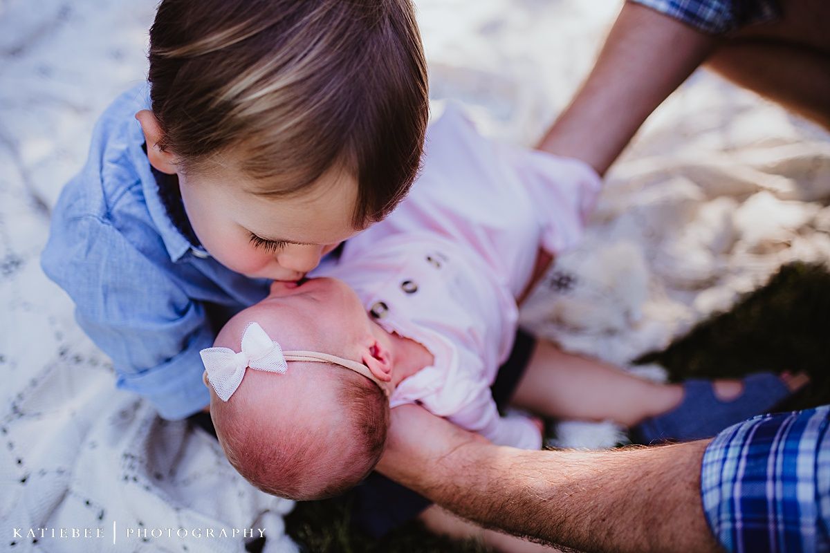 Tender moment captured during outdoor family photoshoot on white blanket.