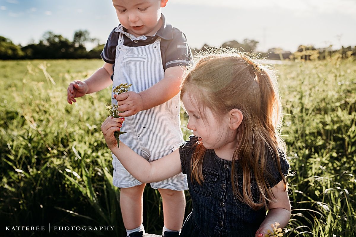 Two children playing together in a grassy field on a sunny afternoon.