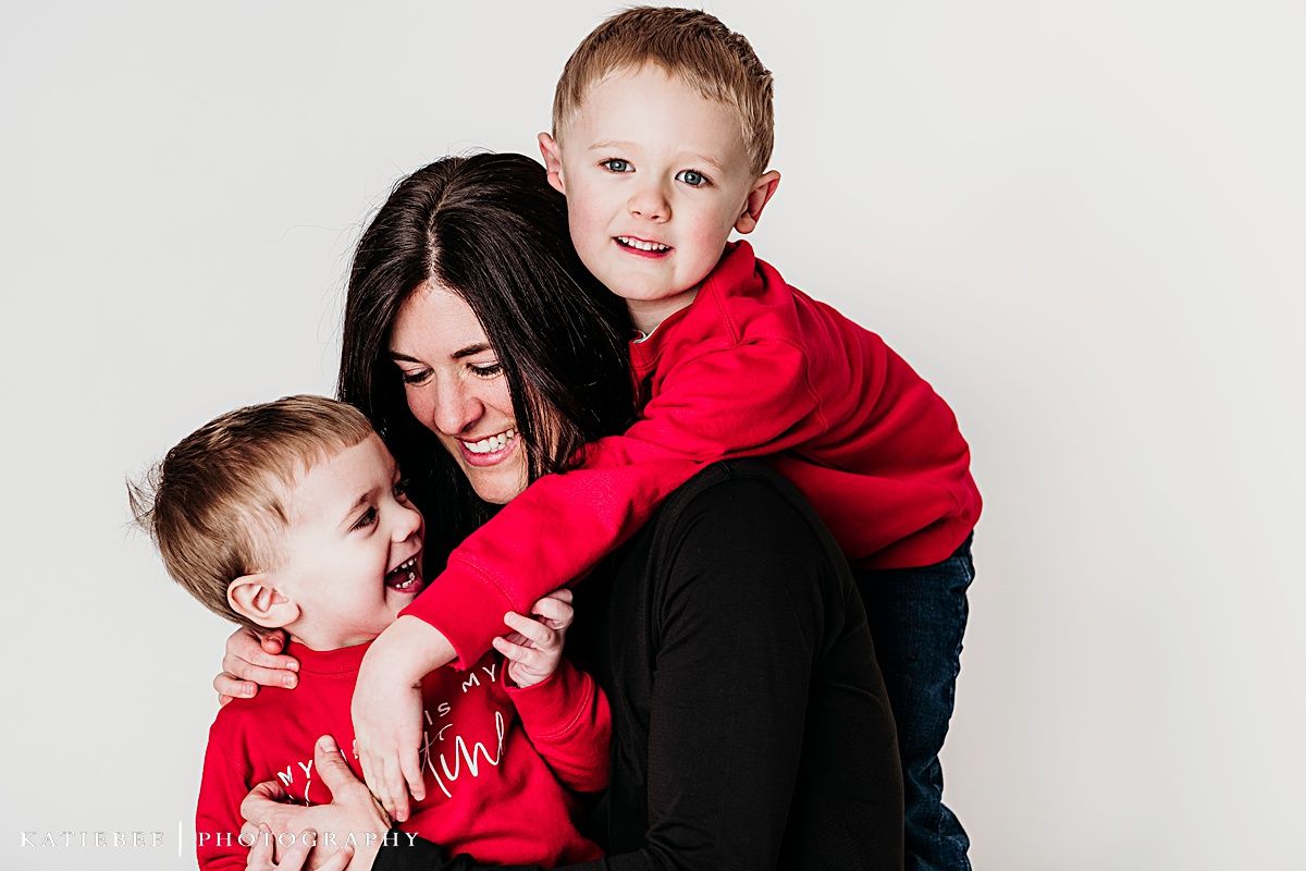 Playful family portrait with red and black clothing against white background.