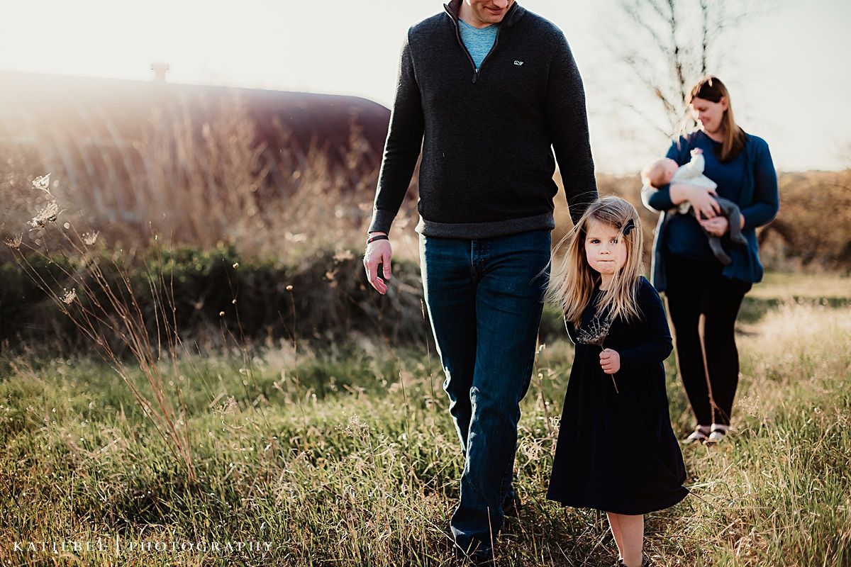 Family enjoying an evening walk together through a natural field setting.
