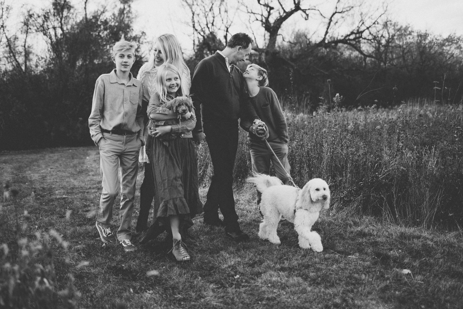 Vintage black and white photo of group with white dog in field.