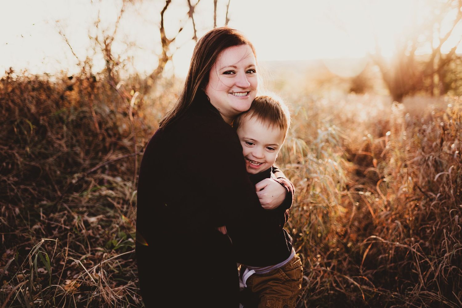 Candid moment between parent and child in tall golden grass.