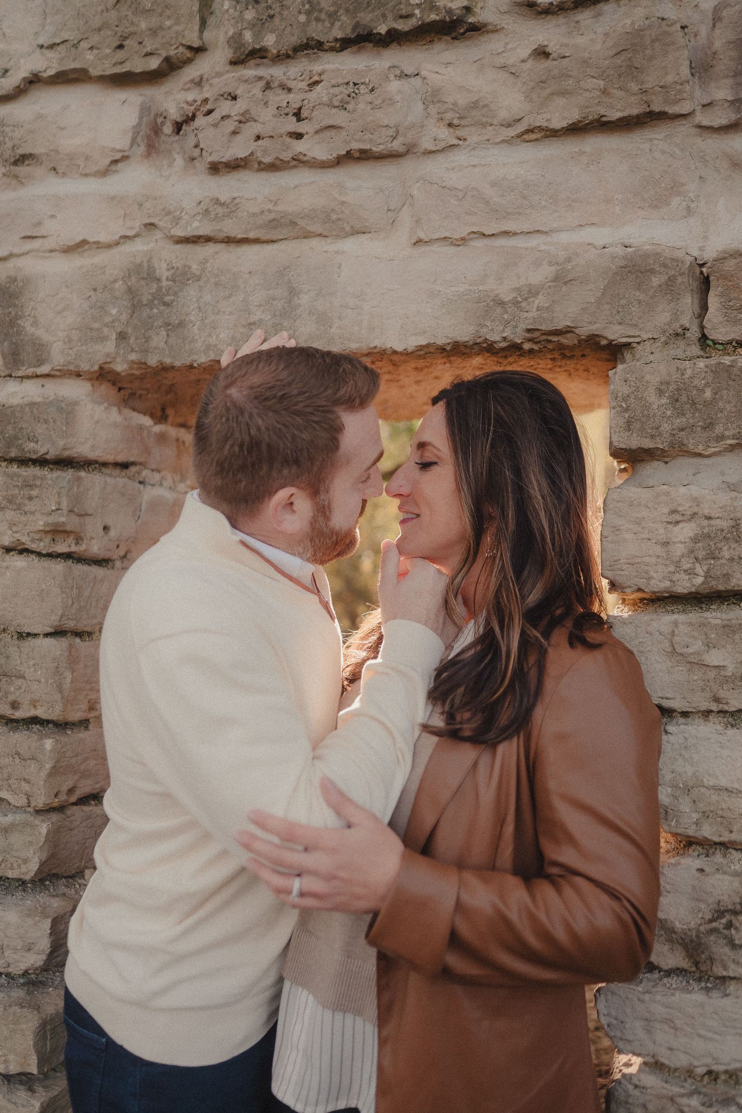 Intimate family portrait series showing tender moments against a stone wall backdrop.